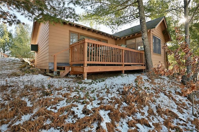 snow covered rear of property with a wooden deck