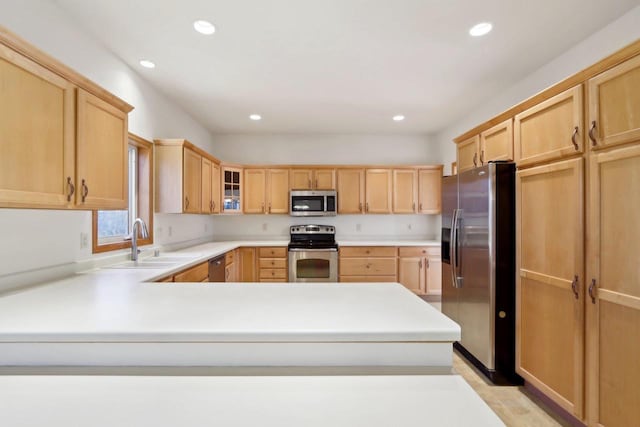 kitchen with kitchen peninsula, appliances with stainless steel finishes, light brown cabinets, and sink