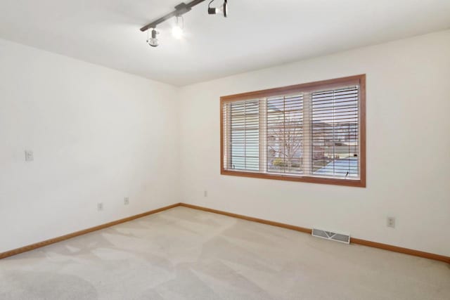 spare room featuring carpet and rail lighting