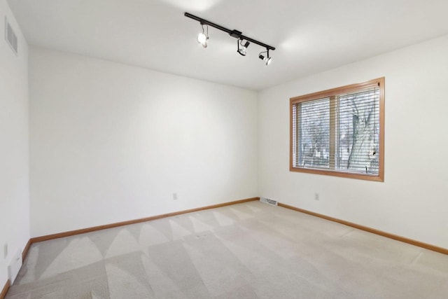 carpeted spare room featuring track lighting