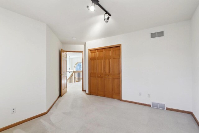 carpeted empty room featuring rail lighting