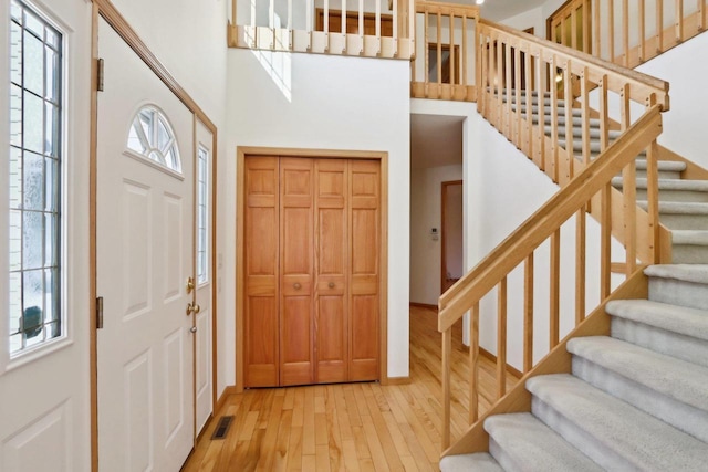 foyer with hardwood / wood-style flooring and a towering ceiling