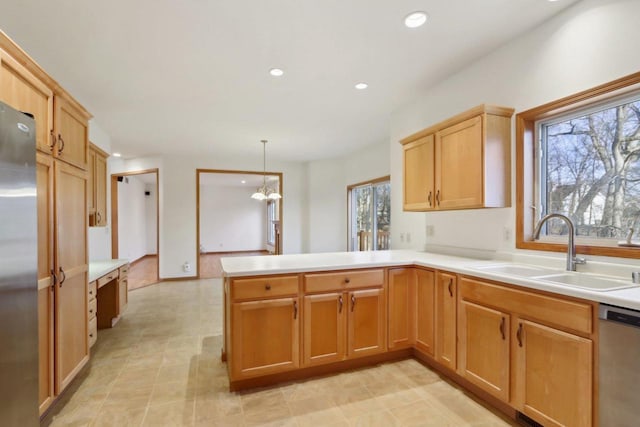 kitchen with sink, stainless steel appliances, a notable chandelier, kitchen peninsula, and decorative light fixtures