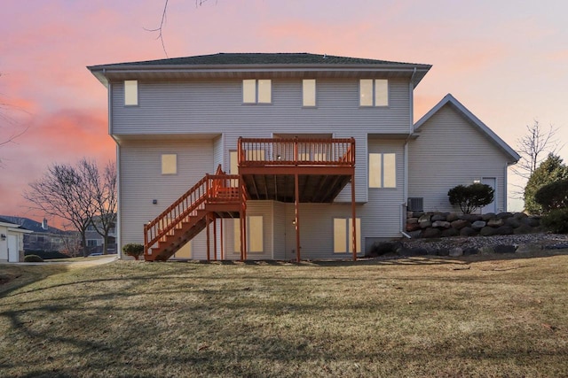 back house at dusk featuring a lawn and a wooden deck