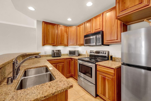 kitchen with sink, appliances with stainless steel finishes, light tile patterned flooring, light stone counters, and kitchen peninsula