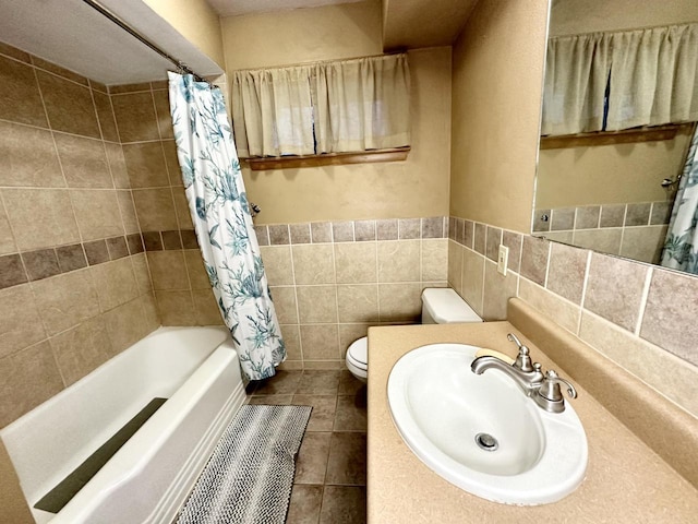 full bathroom with shower / bathtub combination with curtain, tile patterned flooring, toilet, vanity, and tile walls