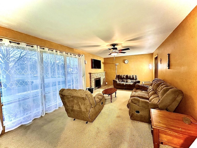 carpeted living room featuring a stone fireplace and ceiling fan