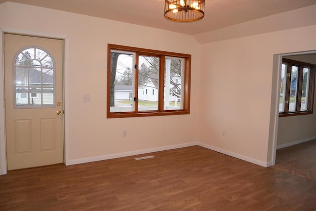 entrance foyer with a notable chandelier, a healthy amount of sunlight, and dark hardwood / wood-style flooring