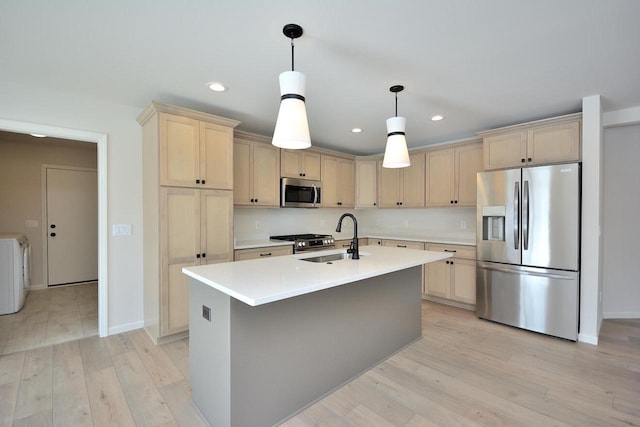 kitchen featuring appliances with stainless steel finishes, sink, hanging light fixtures, and light hardwood / wood-style floors