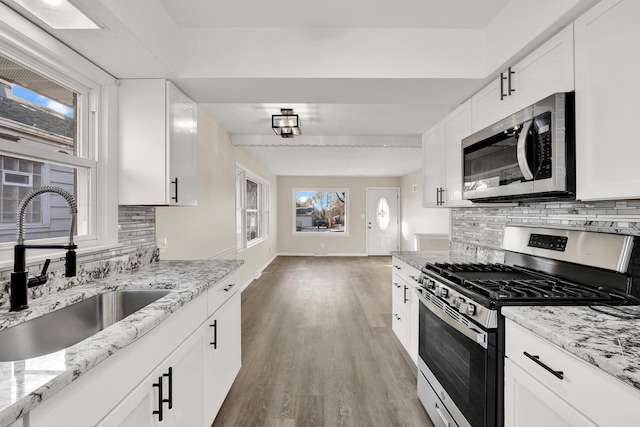 kitchen featuring backsplash, sink, white cabinets, and stainless steel appliances