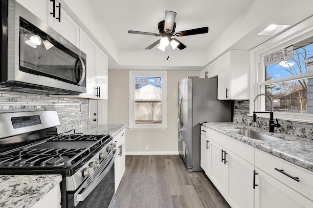 kitchen featuring white cabinets, sink, light hardwood / wood-style flooring, decorative backsplash, and stainless steel appliances