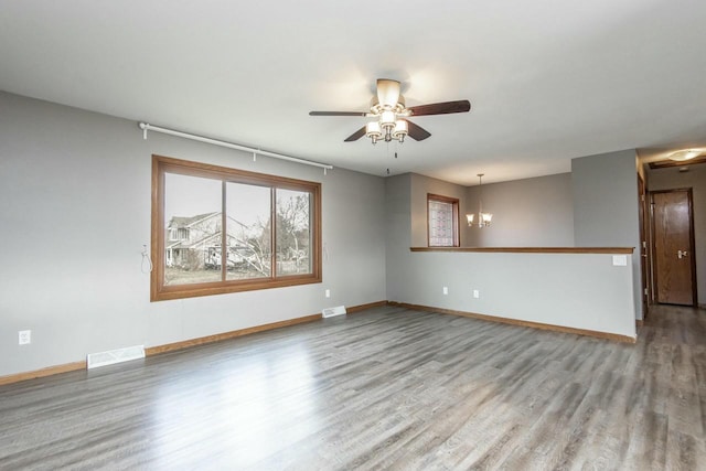 empty room featuring ceiling fan with notable chandelier and light hardwood / wood-style floors