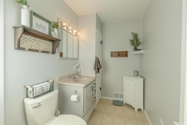 bathroom with toilet, vanity, and tile patterned floors