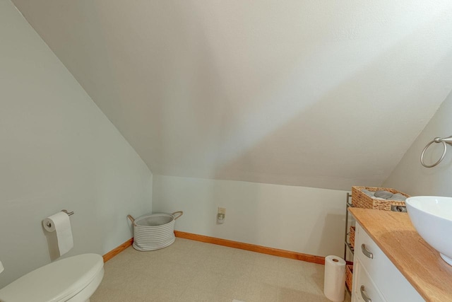 bathroom featuring vanity, toilet, and lofted ceiling