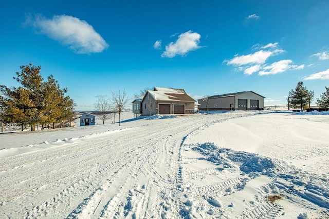 yard layered in snow featuring an outbuilding and a garage