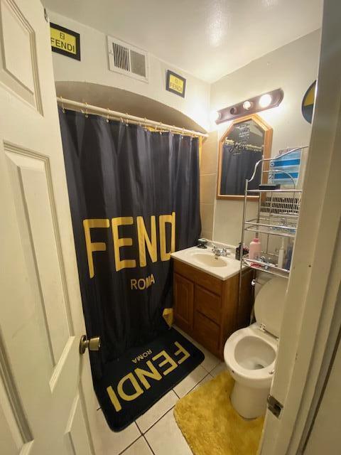 bathroom with tile patterned floors, vanity, curtained shower, and toilet