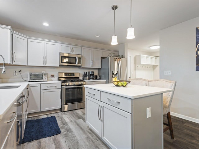 kitchen featuring a kitchen bar, a center island, stainless steel appliances, and hardwood / wood-style flooring