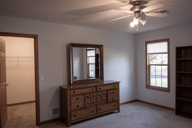 carpeted bedroom with ceiling fan, a spacious closet, and a closet