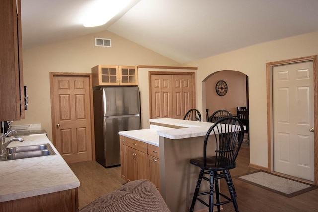 kitchen with stainless steel refrigerator, sink, hardwood / wood-style flooring, a kitchen island, and lofted ceiling