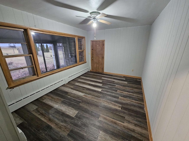 spare room featuring dark hardwood / wood-style floors, ceiling fan, a baseboard heating unit, and wood walls