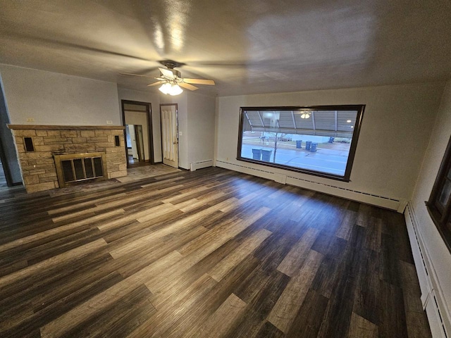 unfurnished living room featuring ceiling fan, dark hardwood / wood-style flooring, a fireplace, and a baseboard heating unit