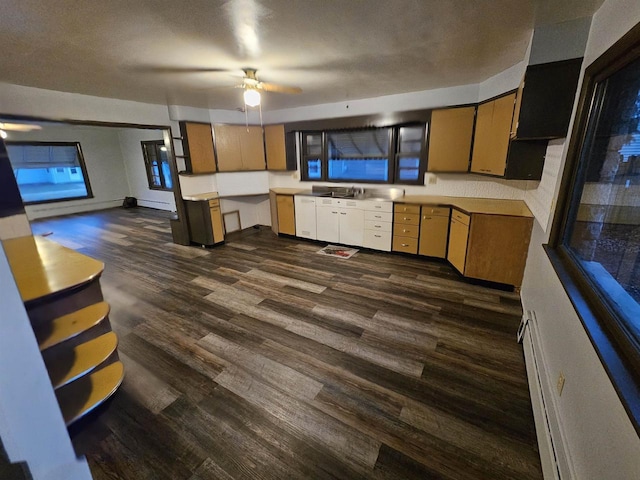 kitchen with ceiling fan, sink, a baseboard radiator, dark hardwood / wood-style flooring, and a textured ceiling