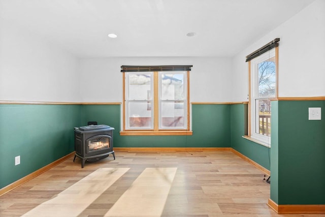 living area with light hardwood / wood-style flooring, a wood stove, and plenty of natural light