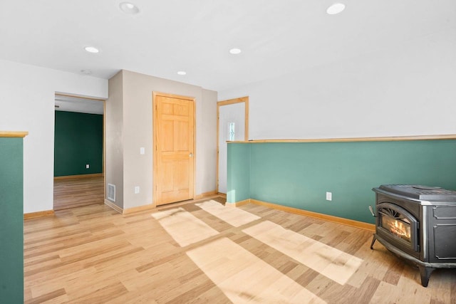 spare room with light hardwood / wood-style floors and a wood stove