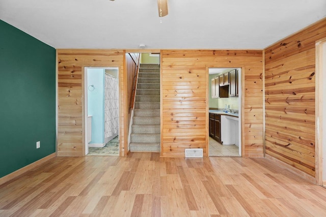 interior space featuring light wood-type flooring, wooden walls, and sink