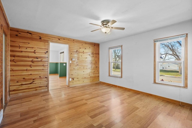 spare room featuring plenty of natural light, light hardwood / wood-style floors, and wooden walls