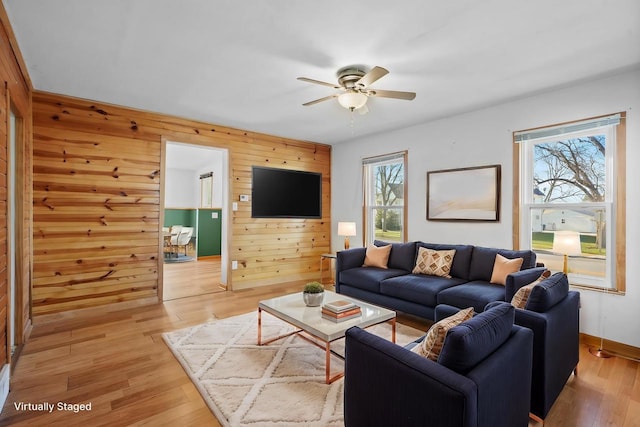 living room featuring plenty of natural light, wood walls, and light hardwood / wood-style floors