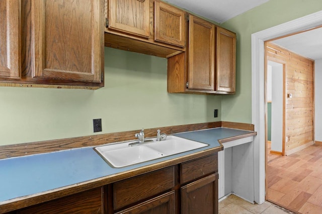 kitchen featuring light hardwood / wood-style floors, sink, and wooden walls