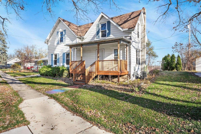 view of front facade featuring a front yard, cooling unit, and covered porch