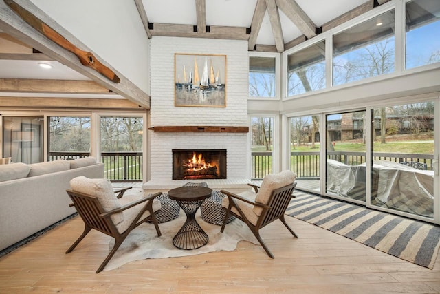 sunroom / solarium with beamed ceiling, a brick fireplace, and plenty of natural light