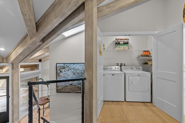 laundry area with light hardwood / wood-style floors, a skylight, and washing machine and clothes dryer