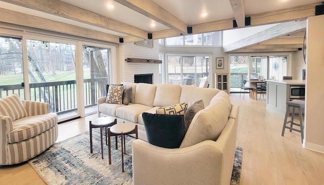 living room featuring plenty of natural light, light hardwood / wood-style floors, and a brick fireplace