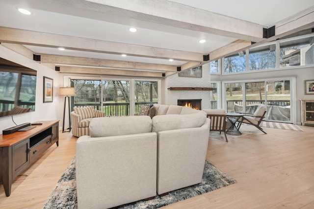 living room featuring beam ceiling, light wood-type flooring, and a wealth of natural light