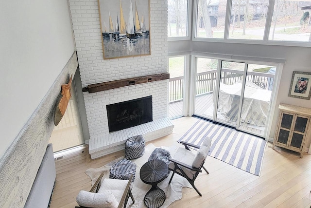 living room with a fireplace, light hardwood / wood-style floors, and a high ceiling