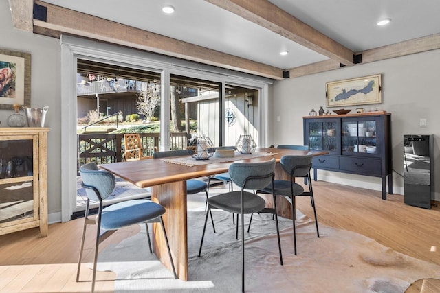 dining room featuring beamed ceiling and light hardwood / wood-style flooring