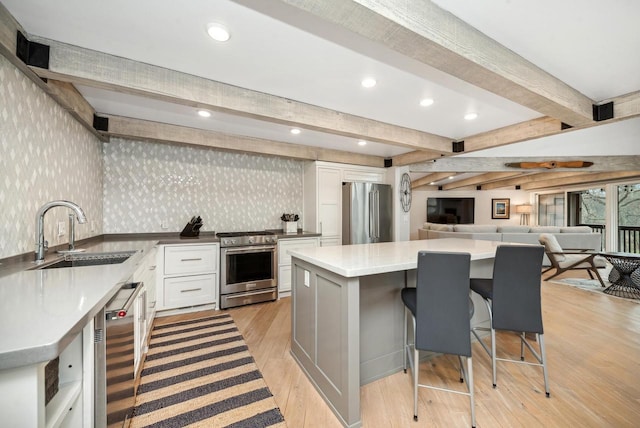 kitchen featuring a breakfast bar, sink, light wood-type flooring, white cabinetry, and stainless steel appliances