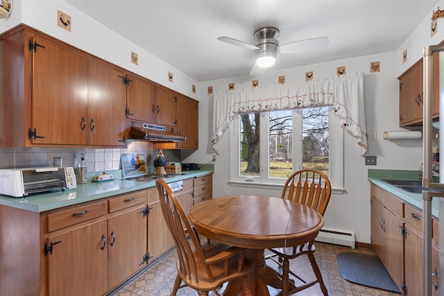 kitchen with backsplash, extractor fan, ceiling fan, a baseboard heating unit, and stainless steel gas cooktop