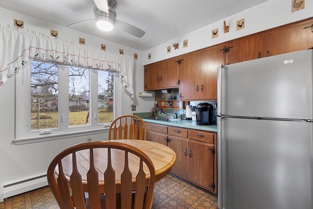 kitchen with stainless steel fridge, ceiling fan, baseboard heating, and sink