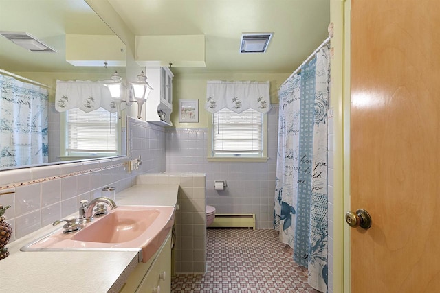 bathroom with tile patterned floors, a healthy amount of sunlight, tile walls, and a baseboard radiator