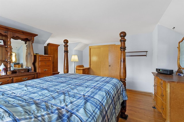 bedroom with light hardwood / wood-style floors and lofted ceiling