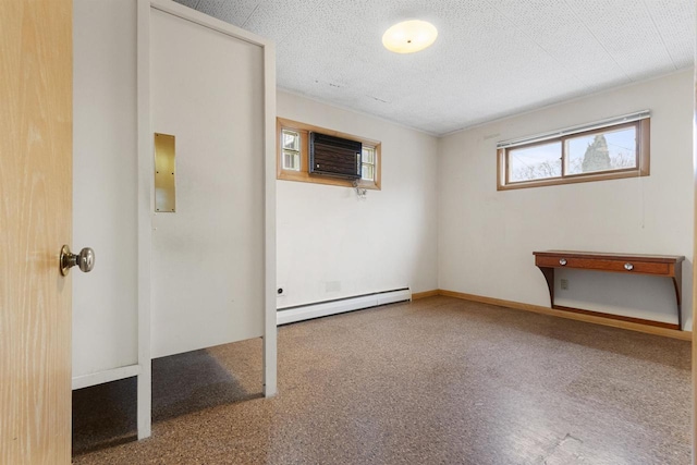 interior space featuring a textured ceiling, an AC wall unit, and a baseboard heating unit