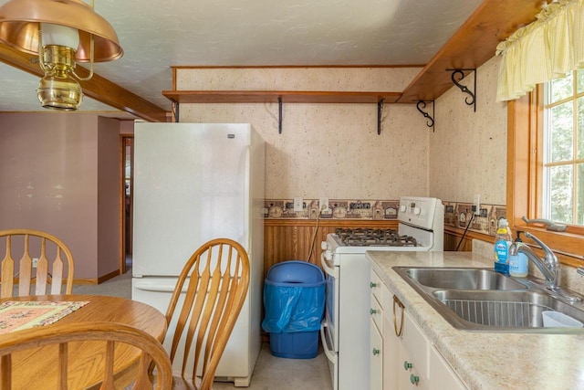 kitchen featuring sink, white cabinets, and white appliances