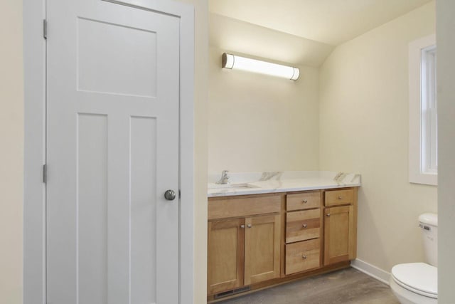 bathroom with hardwood / wood-style floors, vanity, toilet, and vaulted ceiling