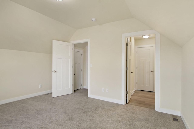 additional living space featuring light carpet and vaulted ceiling