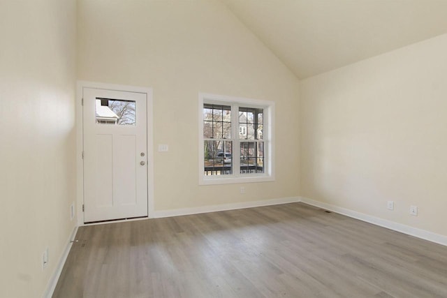 foyer entrance with high vaulted ceiling and light hardwood / wood-style flooring