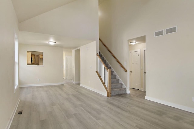 unfurnished living room featuring a high ceiling and light wood-type flooring